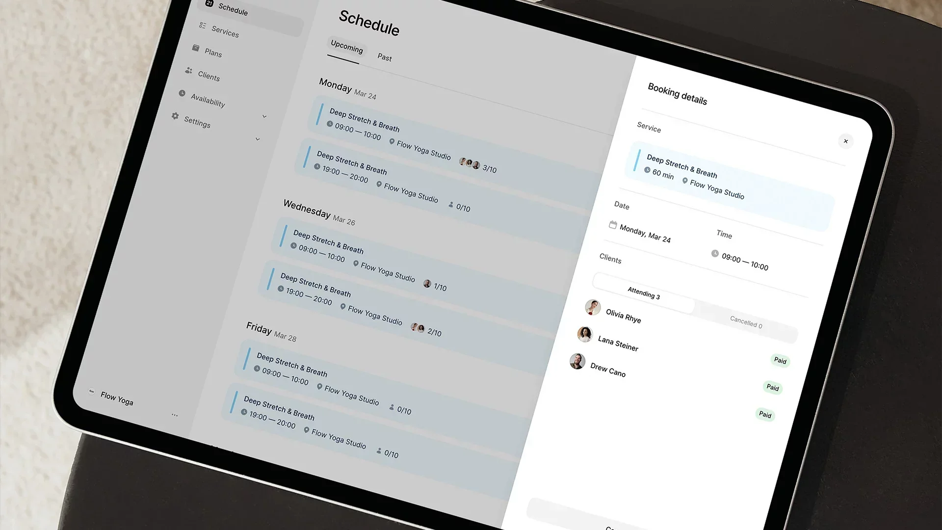 Person holding a smartphone showing a studio class booking screen with available time slots and price
