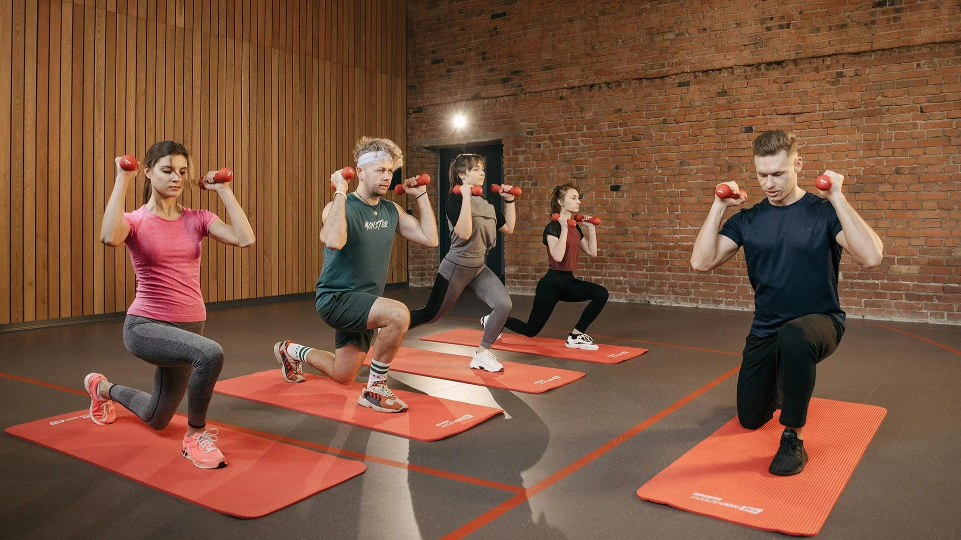 Personal trainer leading a group workout session indoors – fitness class with dumbbells and mats, ideal setting for booking software for trainers