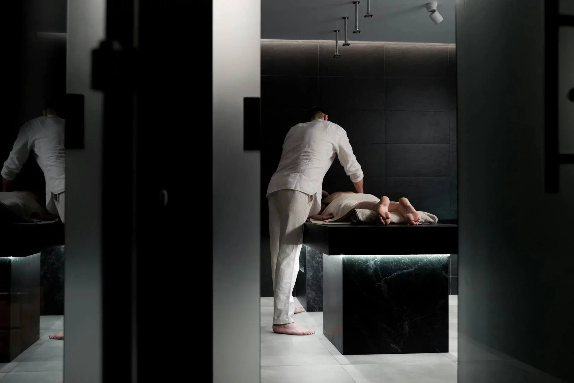 Massage therapist giving a client a massage in a dimly lit spa treatment room