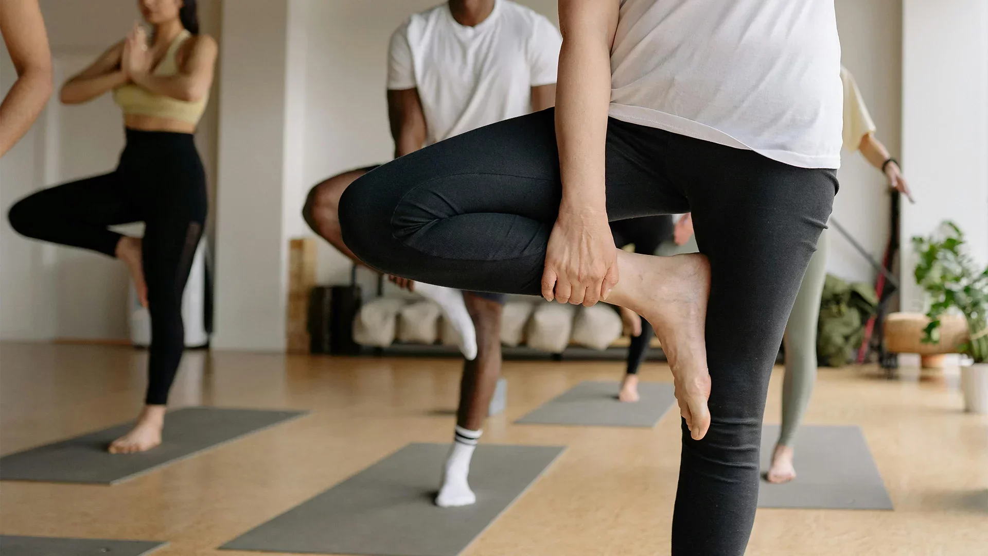Yoga students practicing balance poses in a studio during a class—representing organized scheduling and online booking for yoga sessions